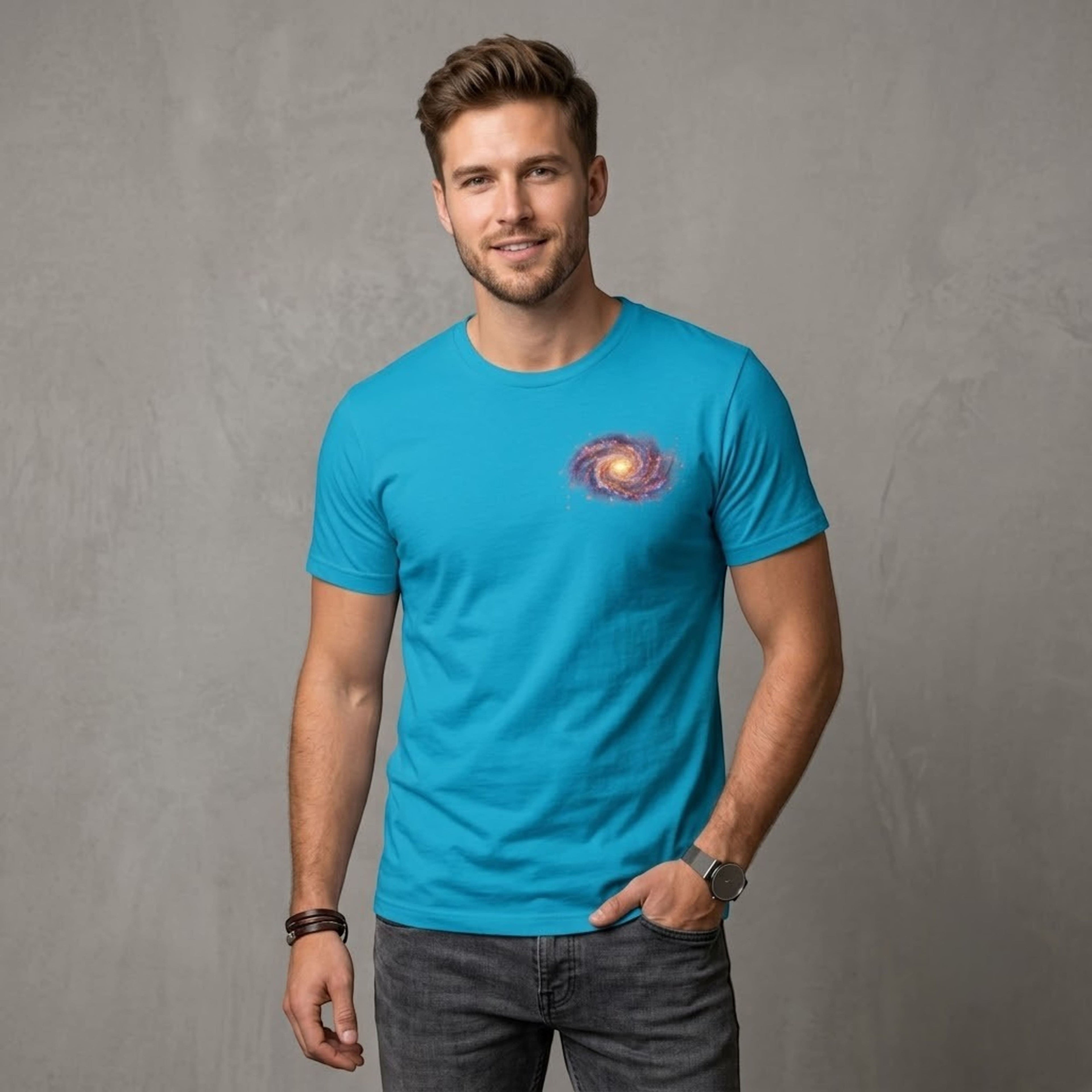 A man wearing a bright blue Chromatic cotton t-shirt featuring a small spiral galaxy graphic on the chest.