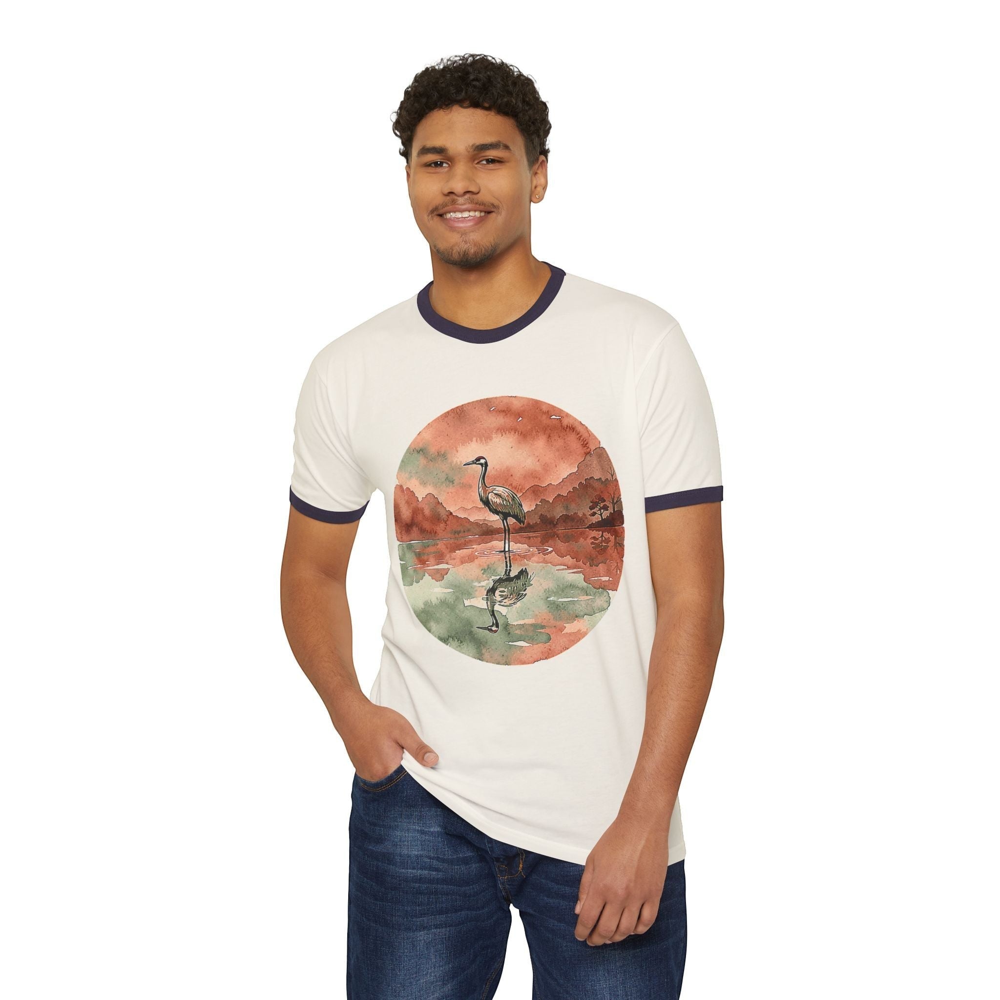 A man wearing a Chromatic white ringer t-shirt with a circular watercolor print of a crane reflecting in a pond.