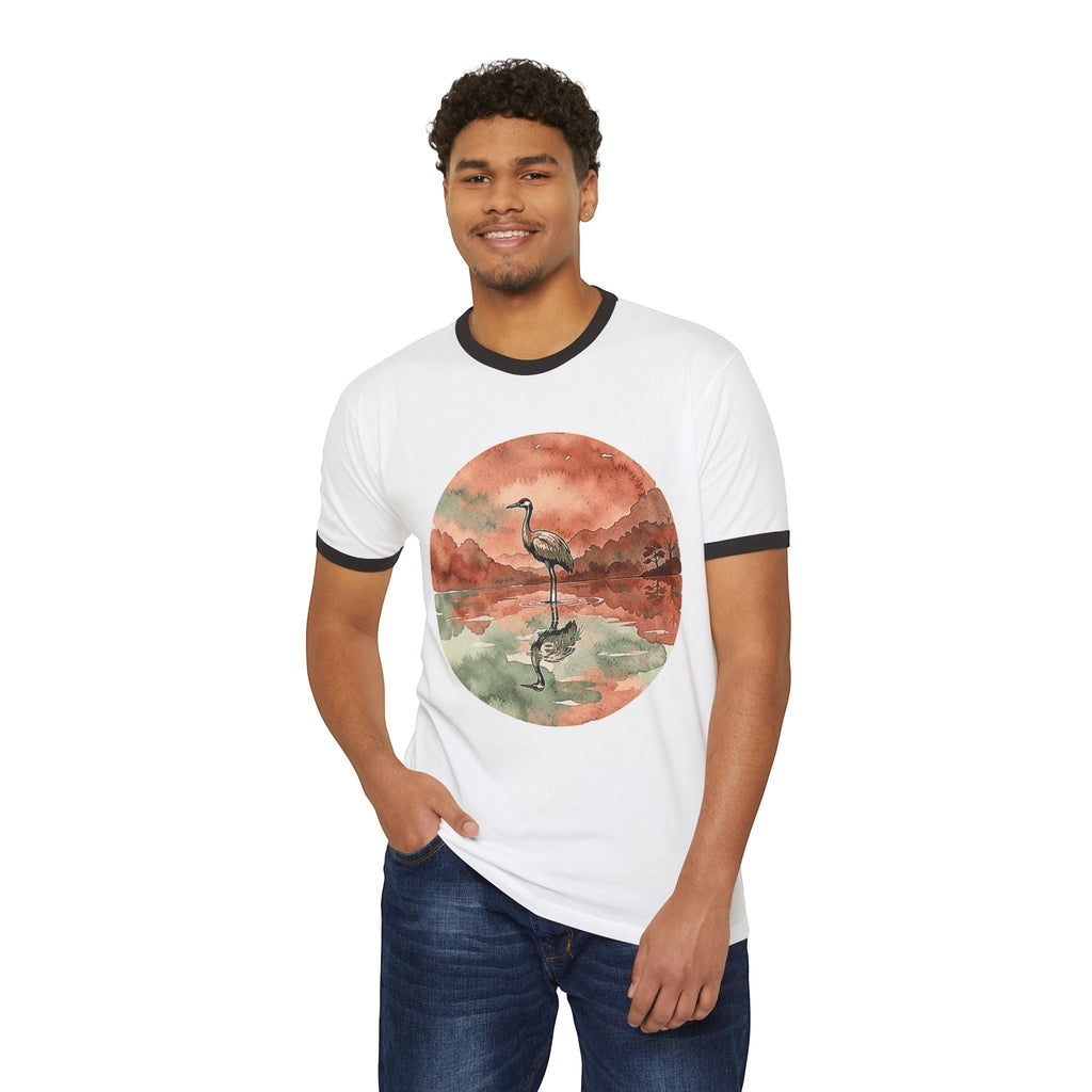 A man wearing a white Chromatic ringer tee with a watercolor crane and pond graphic, featuring black collar trim.